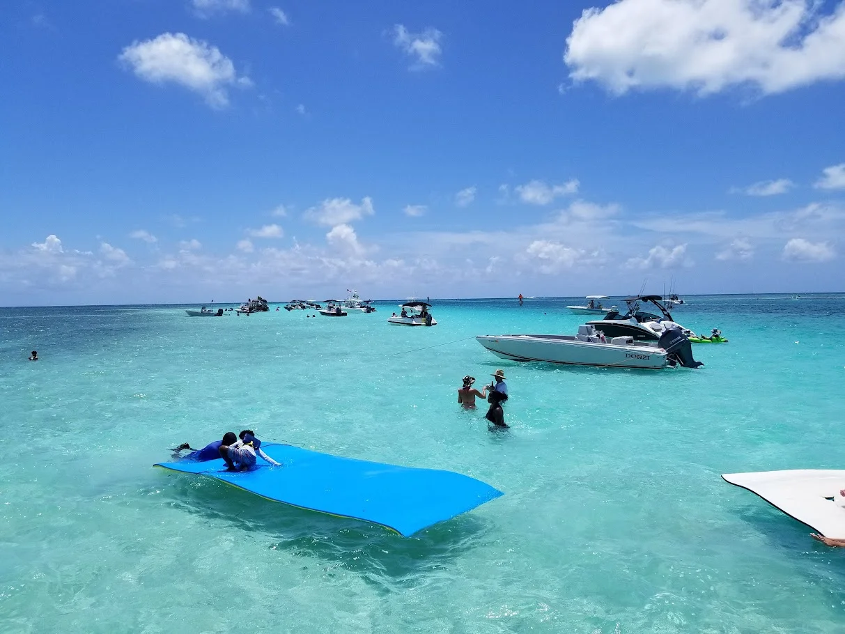 Several boats anchored up at a sandbar with a water mat for relaxation