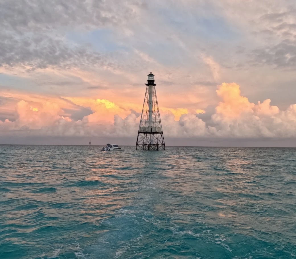 Lighthouse in Islamorada Florida with boat next to it and beautiful clouds