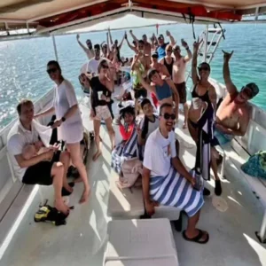 A large group of people cheering and waving from the deck of a Clearly Unique Charters boat.