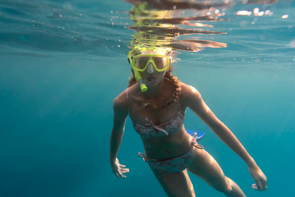Beginner woman snorkeling with mask in shallow ocean water