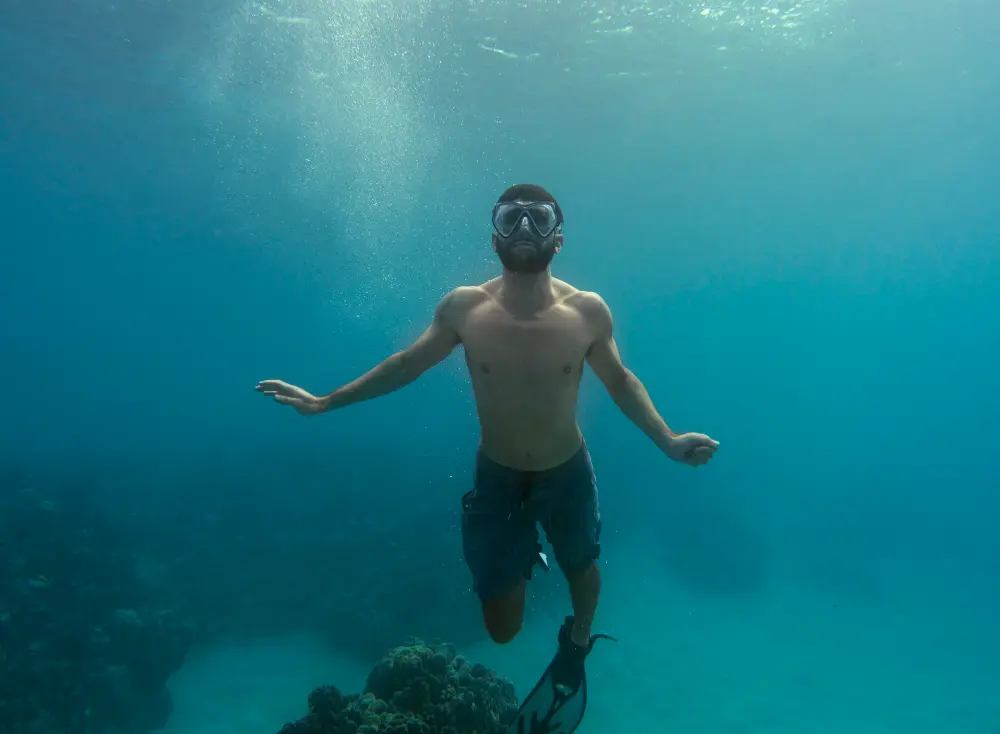 Snorkeler swimming above coral reef enjoying ocean view