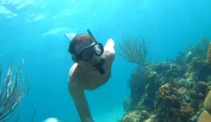 Man snorkeling underwater with a snorkel mask on next to coral