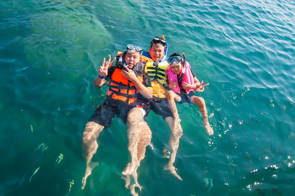 Family snorkeling together in shallow clear ocean water