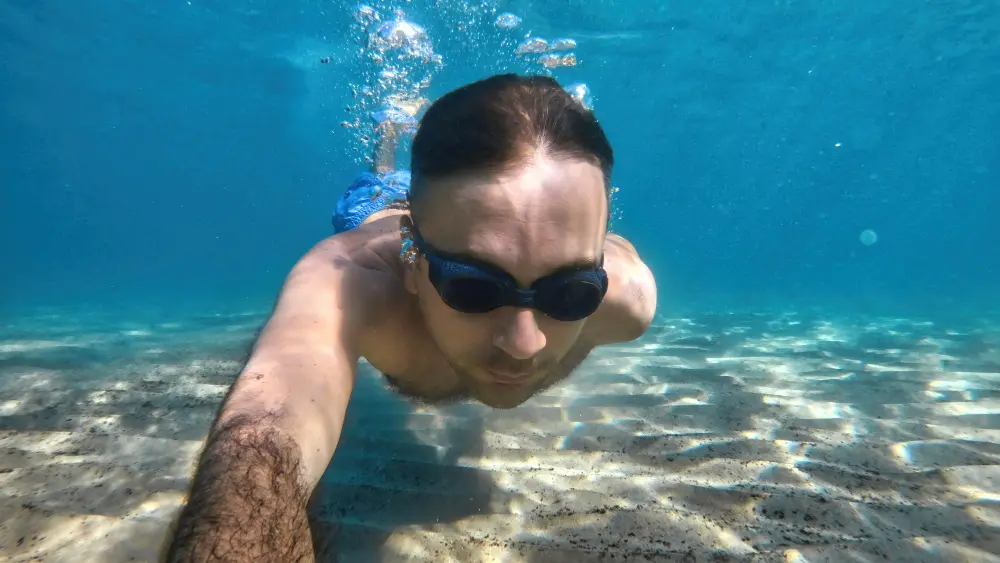 Man snorkeling with mask and goggles in clear ocean water