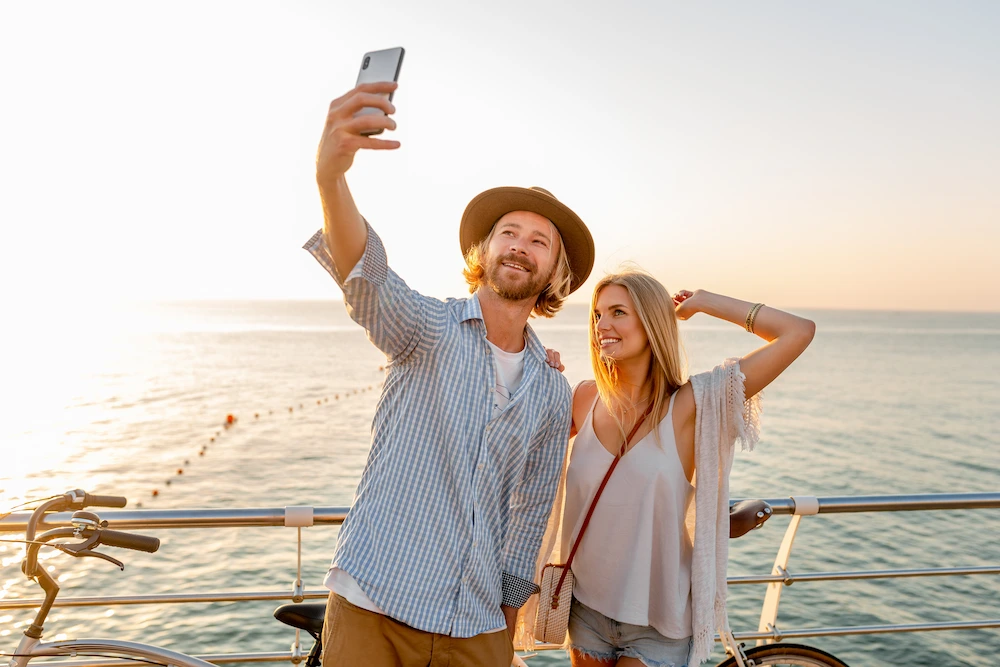 Happy couple taking a selfie on a boat deck at sunset