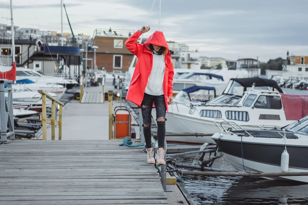 Person sitting in a small boat under cloudy skies while looking across the water